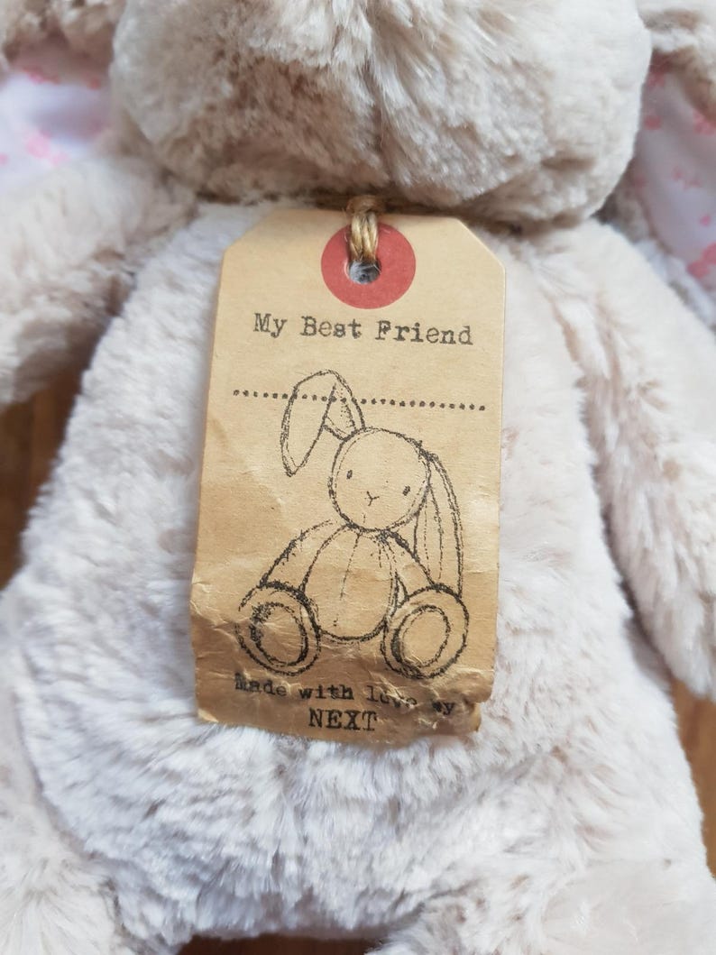 May include: A soft, beige bunny toy with a tag that says "My Best Friend." The tag has a bunny sketch and the text "Made with love by NEXT." The bunny has pink detailing on its ears.