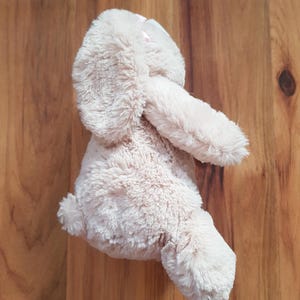May include: A soft, light brown bunny rabbit toy with long ears and a small, fluffy tail. The bunny is made of a soft, textured material. The toy is designed for children and is suitable for cuddling. The bunny is a light beige colour.