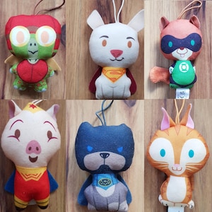 Puede incluir: Conjunto de siete peluches, cada uno con un personaje animal diferente que lleva un disfraz de superhéroe. Los personajes incluyen una tortuga, un perro, un mapache, un cerdo, un perro, un gato y un gato. Los juguetes están hechos de tela suave y de felpa y tienen detalles bordados.