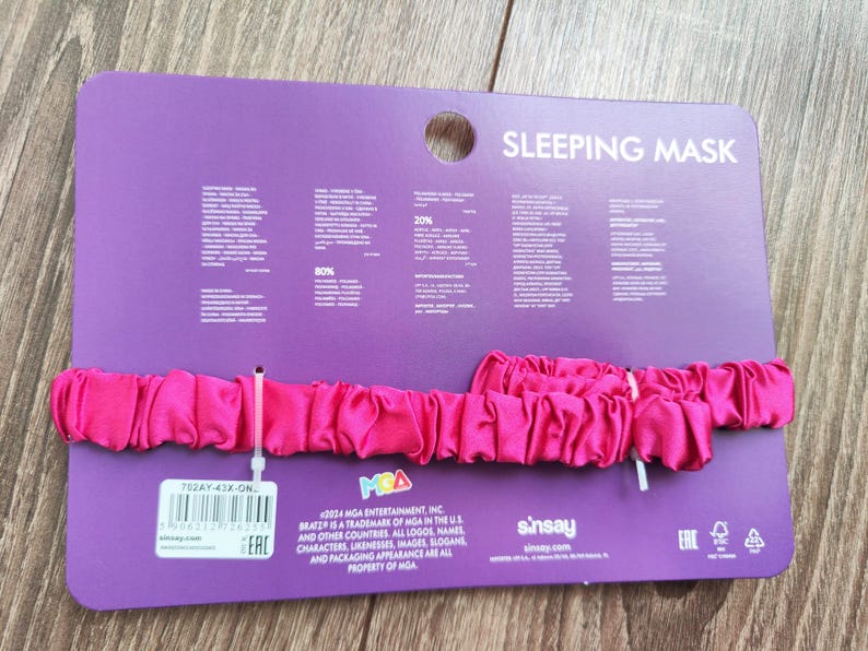 Pu&ograve; includere: Una maschera per dormire in raso rosa con il testo "SLEEPING MASK" sulla confezione. La confezione include anche il testo "BRATZ" e "MGA ENTERTAINMENT, INC."