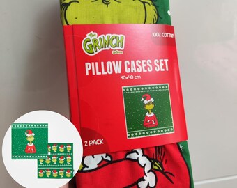 Peut inclure: Un ensemble de deux taies d'oreiller sur le thème du Grinch, chacune mesurant 40 x 40 cm. Les taies d'oreiller sont rouges et vertes, avec un motif répété du Grinch portant un chapeau de Père Noël. L'emballage indique "The Grinch Pillow Cases Set".