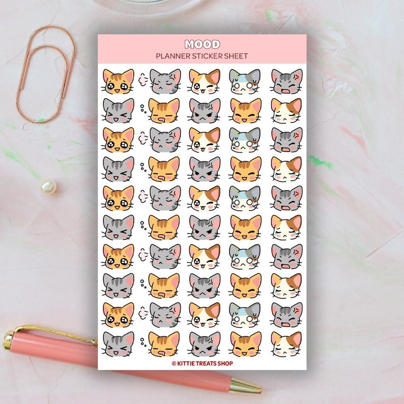 Pu&ograve; includere: Un foglio di adesivi per planner con una variet&agrave; di facce di gatti carini con diverse espressioni. Gli adesivi sono su uno sfondo bianco con un'intestazione rosa che dice "Mood Planner Sticker Sheet".
