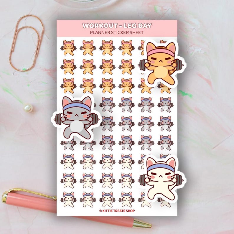 May include: Planner sticker sheet featuring cartoon cats lifting weights. The sheet includes the text "WORKOUT - LEG DAY PLANNER STICKER SHEET" at the top. The stickers are in shades of orange, gray, and white, with blue headbands. The stickers are from Kittie Treats Shop.