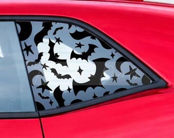 May include: A black vinyl decal applied to a car window featuring a repeating pattern of silhouettes including bats, crescent moons, and various sizes of four-pointed stars. The design covers the entire surface of the triangular rear side window.