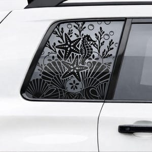 May include: A black vinyl decal applied to a car window featuring an intricate underwater scene. The design includes two starfish, a seahorse, various seashells, a sand dollar, and seaweed silhouettes against the transparent glass surface.