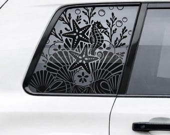 May include: A black vinyl decal applied to a car window featuring a detailed underwater scene. The design includes two starfish, a seahorse, various seashells, a sand dollar, and aquatic plants arranged in a dense, layered composition.