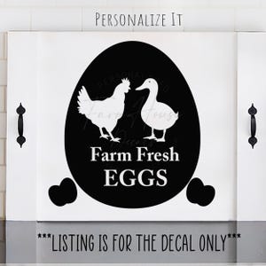 May include: A white farmhouse-style sign with a black egg shape in the center. Inside the egg are white silhouettes of a chicken and a duck, with the words "Farm Fresh EGGS" in white. The text "PERSONALIZE IT" is at the top.