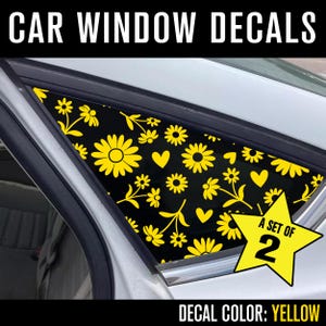 May include: Car window decals with a yellow floral pattern on a black background. The decals feature various flowers and hearts. The text "CAR WINDOW DECALS" is at the top. A yellow star graphic indicates "A SET OF 2". The decal color is yellow.
