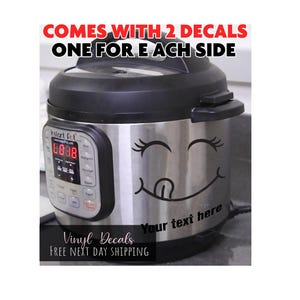 May include: A stainless steel electric pressure cooker with a black lid and control panel. A black vinyl decal featuring a winking face with a tongue sticking out is applied to the front, with the text Your text here printed below the face.