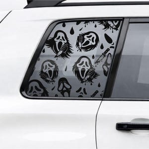May include: Black and white car window decal featuring a repeating pattern of a screaming ghost face holding a knife, with blood drop accents. The decal is applied to the rear passenger window of a white car.