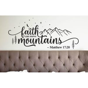 May include: A black wall decal featuring the text faith can move mountains and Matthew 17:20. The design includes a mountain range silhouette, pine trees, a bird, and small stars, all rendered in a clean, script and sans-serif typography.