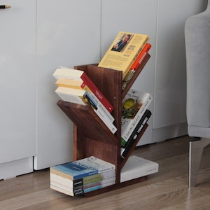 Könnte beinhalten: Ein hölzerner Bücherregal in Form eines Baumes mit mehreren Ästen, das eine Vielzahl von Büchern beherbergt. Das Bücherregal steht auf einem Holzboden.