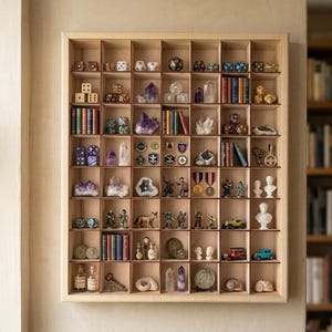 Può includere: Una vetrina in legno con numerosi piccoli scomparti, ognuno contenente una varietà di oggetti da collezione. Gli oggetti includono dadi, cristalli, libri in miniatura, statuette e piccoli veicoli. La vetrina è montata su una parete di colore neutro.