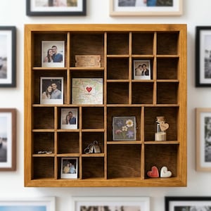 Può includere: Una scatola di legno con più scomparti, che espone vari oggetti. Include fotografie, un biglietto, una mappa con un cuore, una piccola bottiglia di vetro e cuori decorativi. La scatola è di colore marrone caldo.