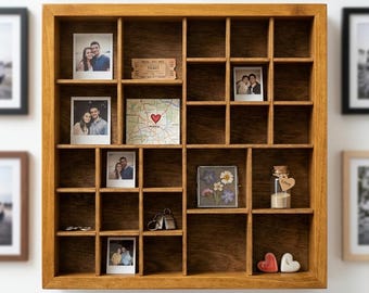 May include: A square wooden shadow box display case with multiple compartments containing various personal items including polaroid photographs, a map with a heart, a small glass bottle, keys, and heart-shaped decorative objects.