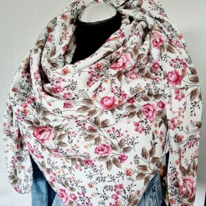 Könnte beinhalten: Weißer Schal mit einem Blumenmuster aus rosa Rosen und braunen Blättern. Der Schal ist über einem schwarzen Schaufensterkopf und einer Jeansjacke drapiert.