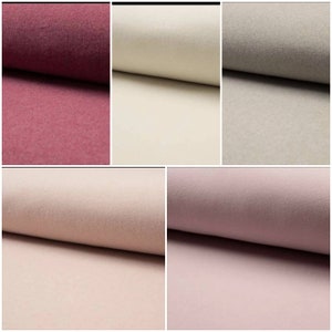 Könnte beinhalten: Stoffmuster in verschiedenen Rosa-, Beige- und Mauve-Tönen. Die Stoffe sind gerollt und zeigen ihre Textur und Farbvariationen. Die Muster umfassen ein tiefes Burgunderrot, Creme und ein helles, staubiges Rosa.