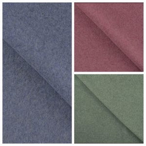 Könnte beinhalten: Drei Stoffmuster aus Filz in verschiedenen Farben. Das größte Muster ist ein gedämpftes Blau-Grau, gefaltet, um die Textur zu zeigen. Die anderen beiden Muster sind ein staubiges Rosa und ein gedämpftes Grün, jeweils gefaltet, um die Textur des Stoffes zu zeigen.