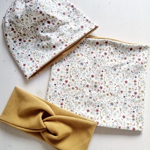 Könnte beinhalten: Ein Set aus drei Stirnbändern mit Blumenmuster. Das Set beinhaltet eine Mütze, einen Halsschlauch und ein gebundenes Stirnband. Die Mütze und der Halsschlauch sind weiß mit einem kleinen Blumenmuster in den Farben Rosa, Rot und Grau. Das Stirnband ist einfarbig senfgelb.