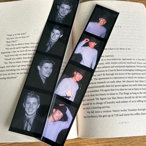 May include: Two black and white photo strips with images of a young man. The photo strips are folded in half and are on a book with the word "LIFE" printed on the cover.