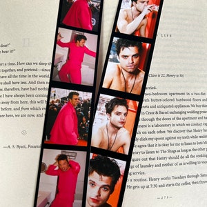 May include: A set of six bookmark photos featuring a man with blue eyes and short brown hair. The photos are arranged in a vertical strip, with the man wearing a pink shirt in some photos and shirtless in others. The photos are printed on a white background with black borders.