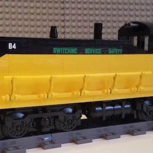 May include: A yellow and black toy train engine with the words "Switching Service Safety" and "South Buffalo Railway" printed on the side. The engine has the number "84" printed on it.