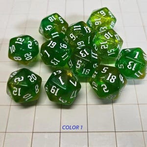 May include: A collection of green and yellow polyhedral dice with white numbering. The dice are scattered on a white grid surface. The image is well-lit, showcasing the translucent quality of the dice.