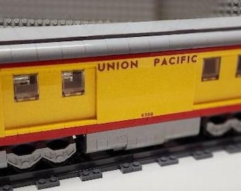May include: A yellow and red toy train car with the words "UNION PACIFIC" printed on the side. The car has a gray roof and several windows. The car is on a black track.