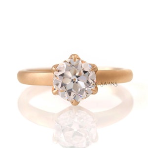 Puede incluir: Un anillo de oro con un diamante redondo y transparente engastado en una montura de seis garras.