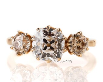 May include: A gold ring with three clear and brown cushion-cut gemstones. The ring is set in a delicate gold band.