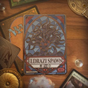 May include: A rectangular trading card featuring a stained-glass style illustration of a dark, multi-limbed creature. The card displays the text ELDRAZI SPAWN, a skull symbol, the word ADD, a colorless mana symbol, and the power/toughness 0/1.