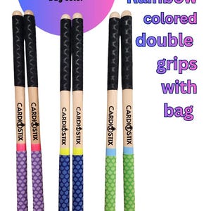 May include: Drum sticks with rainbow-colored double grips. The image shows three pairs of sticks with different grip colors: purple, blue, and green. Each stick has the text "CARDIOSTIX" printed on it. The text "You choose sticks. We choose bag color" is also present.