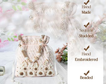 May include: A delicate, hand-beaded drawstring bag with a pearl and gold chain strap. The bag is made of a soft, pink fabric and features intricate floral embroidery. It is adorned with sequins and has a hand-embroidered design. "Hand Made", "Sequins Studded", "Hand Embroidered", and "Beaded" are written on the image.