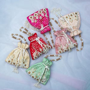 May include: Five colorful drawstring bags with pearl embellishments and tassels. The bags are made of silk and are decorated with floral embroidery. The bags are connected by a pearl chain.