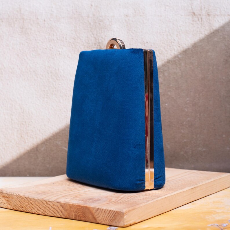 Navy blue suede clutch purse with a gold-tone chain, perfect for elegant evening events.