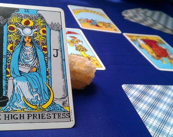 May include: The High Priestess tarot card features a woman in a blue robe sitting on a throne with a crescent moon on her head. The card is surrounded by a black and white border and the text "The High Priestess" is printed at the bottom.