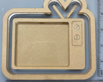 May include: A wooden TV-shaped picture frame. The frame is made of light brown wood and has a retro TV design with an antenna and control buttons. The frame measures approximately 5 inches in height and 5 inches in width.