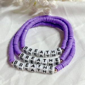 May include: A purple beaded bracelet with the word "breathe" spelled out in white beads.