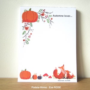 Op de afbeelding: Een witte kaart met een handgeschreven bericht dat "Automne lover..." zegt. De kaart is versierd met een pompoen, herfstbladeren en een vosfamilie. De kaart ligt op een houten oppervlak.