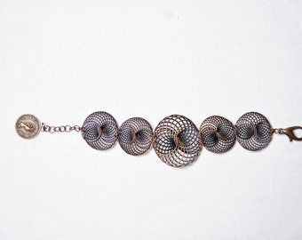 Könnte beinhalten: Kupferfarbenes Armband mit sechs filigranen, kreisförmigen Gliedern mit geometrischem Muster. Das Armband hat einen Münzanhänger und einen Karabinerverschluss. Das Design ist vor weißem Hintergrund.