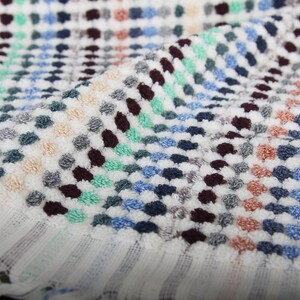 May include: White bath towel with a colorful geometric pattern of small dots in shades of blue, green, red, and brown.
