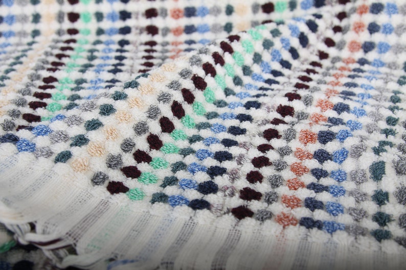 May include: White bath towel with a colorful geometric pattern of small dots in shades of blue, green, red, and brown.