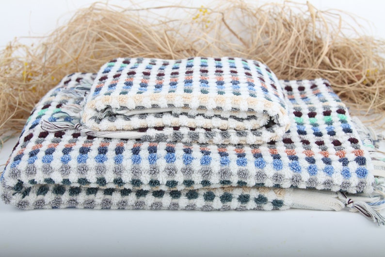 May include: A stack of four colorful towels with a checkered pattern. The towels are made of soft, absorbent cotton and are perfect for drying off after a shower or bath.