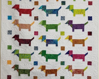 Könnte beinhalten: Eine weiße Steppdecke mit einem Muster aus 18 bunten Dackeln. Jeder Hund ist aus verschiedenen gemusterten Stoffen gefertigt und schwarz umrandet. Die Steppdecke ist mit kleinen Quadraten in verschiedenen Farben verziert.