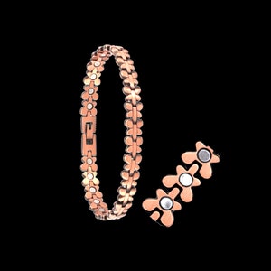 Op de afbeelding: Een roségouden magnetische armband met een bloemvormig ontwerp. De armband is gemaakt van metaal en heeft een sluiting. De armband wordt in twee delen getoond, met de sluiting open.