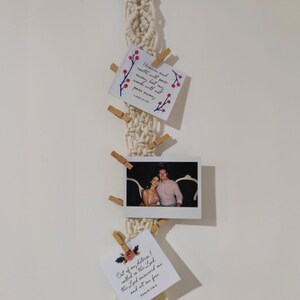 Puede incluir: Una pared colgante de macramé blanca con un anillo de madera en la parte superior. Tres tarjetas están sujetas al macramé con pinzas de madera. Las tarjetas tienen citas inspiradoras y diseños florales. Las citas son "El cielo y la tierra pasarán, pero mis palabras no pasarán. Lucas 21:33" y "De mi angustia clamé al Señor, el Señor me respondió y me puso en libertad. Salmo 18:6".