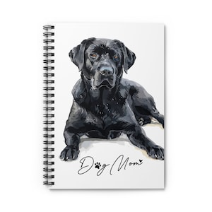 May include: Spiral-bound notebook featuring a watercolor illustration of a black Labrador Retriever. The dog is lying down, with the text "Dog Mom" in cursive below. The notebook has a white background.
