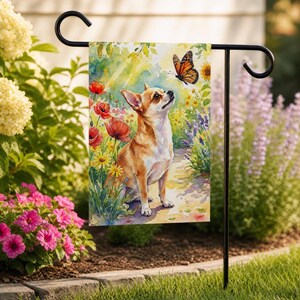 May include: A garden flag featuring a watercolor painting of a Chihuahua dog looking up at a butterfly. The dog is surrounded by colorful flowers, including red poppies, yellow daisies, and purple lavender. The flag is displayed on a black metal garden stake.