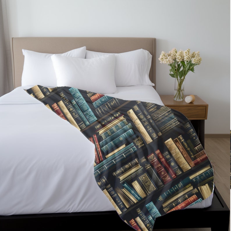 May include: A black and white throw blanket with a pattern of colorful books on a bookshelf. The books have gold accents and are arranged in a diagonal pattern.