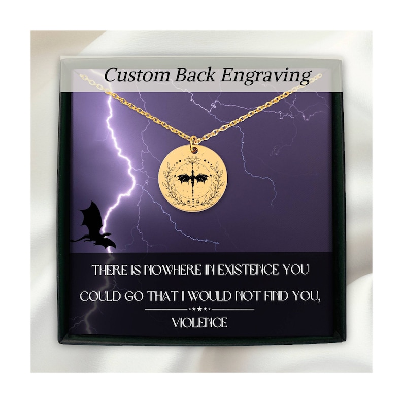 Peut inclure: Un collier en or avec un pendentif rond repr&eacute;sentant une silhouette de dragon noir &agrave; l'int&eacute;rieur d'une couronne. Le pendentif est sur un fond violet avec un motif d'&eacute;clair. Le texte sur la bo&icirc;te indique "Gravure arri&egrave;re personnalis&eacute;e" et "IL N'Y A AUCUN ENDROIT DANS L'EXISTENCE O&Ugrave; TU POURRAIS ALLER QUE JE NE TE TROUVE PAS, VIOLENCE".
